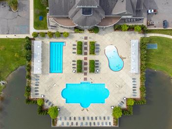 an aerial view of a pool and a swimming pool in front of a house at The Harbours Apartments, Clinton Twp, MI